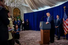 Donald Trump está parado frente a un auricular con micrófono. Detrás está Marco Rubio y, junto a él, una bandera de Estados Unidos. De fondo se ven funcionarios y frente a Trump hay periodistas.