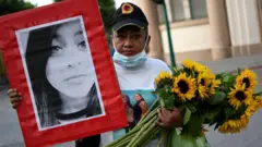 Una mujer sostiene una foto de una niña y unos girasoles durante una manifestación para conmemorar el quinto aniversario de un incendio en un albergue infantil que dejó 41 niñas y adolescentes muertas y 15 heridas, en la Plaza de la Constitución en la Ciudad de Guatemala el 7 de marzo de 2022. (Foto por Johan ORDONEZ / AFP) (Foto por JOHAN ORDONEZ/AFP a través de Getty Images)