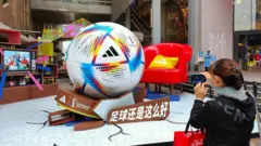 A woman takes a photo of a giant World Cup football in Shanghai, China