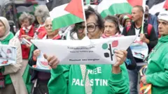 Mujer en una manifestación en París con un barco de papel