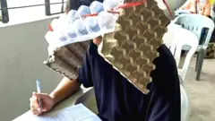 ਫਿਲੀਪੀਨਜ਼ ਵਿੱਚ ਇੱਕ ਕਾਲਜ ਇਮਤਿਹਾਨ ਦੌਰਾਨ ਇੱਕ ਵਿਦਿਆਰਥੀ ਅੰਡੇ ਦੇ ਡੱਬਿਆਂ ਤੋਂ ਬਣੀ ਘਰੇਲੂ ਟੋਪੀ ਪਹਿਨੇ ਹੋਏ