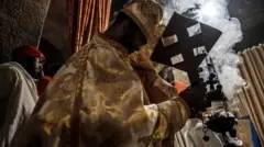 መስቀል የያዙ ቄስ እና የእጣን ጭስ 