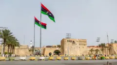 صورة لساحة الشهداء في العاصمة الليبية طرابلس رفع فيها علمان للبلاد. 