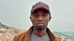 O supervisor da mina de Rubaya, Patrice Musafiri, fotografado na mina com montanhas ao fundo