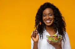Femme américain africain heureux mangeant la salade de légumes