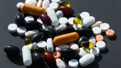 A collection of pills and tablets against a plain background