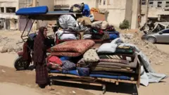 Foto of woman wey stand near her load wey dem pack 