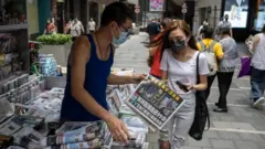 A woman buys a copy of Apple Daily newspaper at a news stand in Hong Kong, China, 18 June 2021.