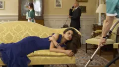 Koltuğa yatmış bir kadın, çevresinde çalışanlar