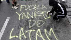 Manifestante pixa mensagem contra EUA durante protesto em Bogotá