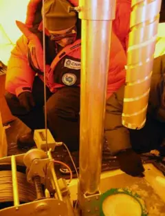 Homem debruçado usa furadeira em gelo