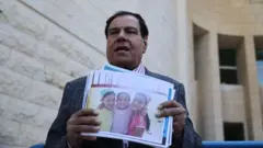 Izzeldin Abuelaish à côté d'une photo de ses trois filles.