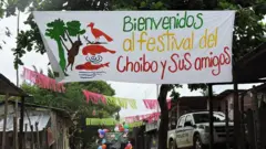 Uma placa em uma vila que diz "Bem-vindo ao Festival Choibo e Amigos"