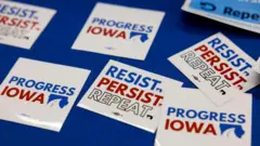Insígnias com os dizeres: Resista. Persista. Repita. Progresso de Iowa.