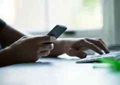Personne tenant un téléphone portable et manipulant un clavier