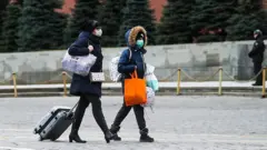 Люди в масках и с сумками на Красной площади.