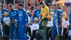 تصویری از افتتاحیه بازی هنگامی که بازیکن‌ها وارد میدان می‌شوند. کپتان‌های افغانستان و افریقای جنوبی در حالی دیده می‌شوند که دست کودکان را هنگام وارد شدن به میدان به دست دارند تا مراسم پیش از بازی را آغاز کنند.