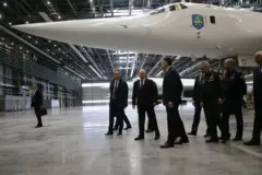 Putin andando com outros homens ao lado de um avião