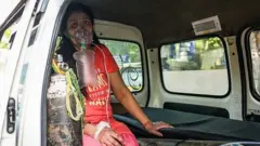 Seorang perempuan menanti ditempatkan di rumah sakit di Delhi.