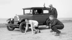 Corredor e motorista de carro aguardam o tiro de largada para uma corrida na praia