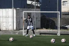 Jovem goleiro defende uma bola durante o treino no campo prestes a ser demolido