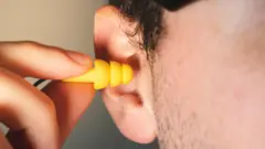 Hombre introduciendo un tapón en el oído.