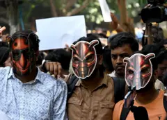 Manifestantes usan máscaras de cucaracha durante una protesta.