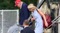 Donald Trump amerikai elnök és tanácsadója, Natalie Harp (jobbra) 2026. augusztus 16-án kiszállnak a Marine One helikopterből a Fehér Ház közelében található Ellipse-en. Trump elnök a New Jersey-i golfklubjában töltött hétvége után tér vissza Washingtonba. 