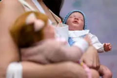 Duas bonecas reborn no colo de uma mulher