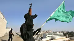 Combatentes do Hamas, um deles com a bandeira do grupo