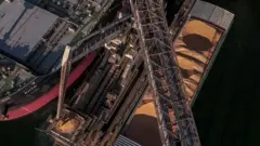 Uma barcaça e um navio graneleiro são carregados com soja no terminal de grãos da Cargill, às margens dos rios Tapajós e Amazonas, em Santarém, estado do Pará, Brasil, na segunda-feira, 29 de agosto de 2025.