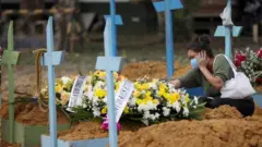 Mulher chora diante de túmulo em Manaus