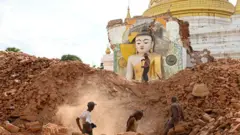 People clear debris of a damaged Buddha statue at Lawkatharaphu pagoda in Inwa on the outskirts of Mandalay in Myanmar