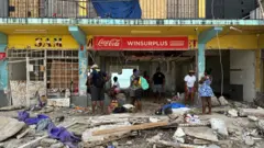 Personas buscan entre los escombros agua y comida.