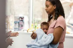 Mãe com aparência distraída e deprimida em consulta médica com seu novo bebê no colo