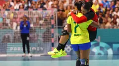 Tamires Araujo, do Brasil, carrega nos braços a rival Albertina Kassoma,one bet zoneAngola, durante uma partidaone bet zonehandebol 