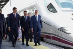 Pedro Sánchez caminha sorridente ao lado de um trem de alta velocidade parado, ao lado do presidente regional da Andaluzia, Juanma Moreno e outras autoridades na inauguração do AVE entre Madri e Granada