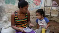 Una mujer alimenta a una niña en el barrio La Bombilla en Caracas.