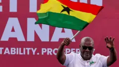 Le candidat à la présidence du Congrès national démocratique (NDC) et ancien président du Ghana, John Dramani Mahama, tient un drapeau national alors qu'il salue ses partisans lors de son dernier meeting de campagne électorale à Accra, au Ghana - 5 décembre 2024