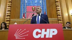 Özel CHP'nin TBMM'deki kürsüsünde konuşuyor. Arkasında Atatürk büstü, kürsünün önünde CHP'nin adı ve logosu var.
