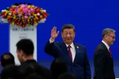 習近平舉手找招呼，背景是藍色底