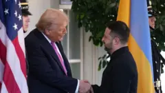 Tramp i Zelenski se rukuju uz osmehe okruženi zastavama Amerike i Ukrajine