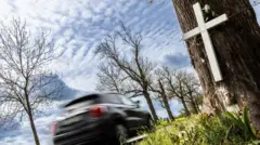 Carro passando sobre cruz memorial