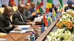 Abategetsi bitabiriye inama isanzwe ya 26 ya CEEAC, i Malabo, muri Guinée équatoriale. Ifoto yatangajwe ku rubuga X n'ibiro bya perezida wa DRC, ku itariki ya 7 Kamena (6) mu mwaka wa 2025. Abategetsi baricaye, imbere yabo hari indangururamajwi n'amabendera mato y'ibihugu, hirya inyuma hari amabendera manini.