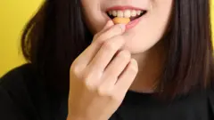 Mulher jovem de camisa preta come uma semente