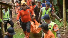 Sejumlah pria mengangkat jenazah dalam kantong berwarna jingga.