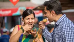 एक महिला आणि पुरुष पाणीपुरी खाताना
