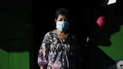 Ms Sutthi wearing a mask in front of her house