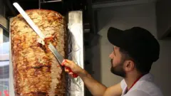 Seorang penjual memotong daging di kedai Mustafas Gemüse Kebap di Berlin, Jerman.