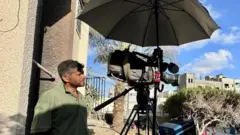 المصور الفلسطيني حسام المصري مع كاميرته أثناء عمله في مستشفى ناصر في خان يونس جنوب قطاع غزة